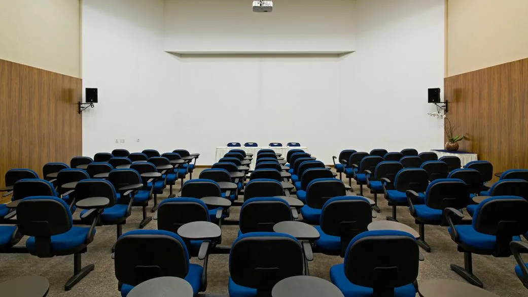 Auditório montado para congresso, com cadeiras enfileiradas e palco ao fundo